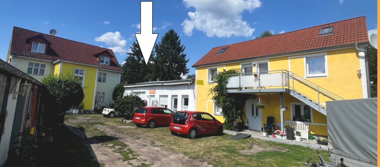 Blick auf den Hof, der Pfeil zeigt auf das Praxisgebäude
