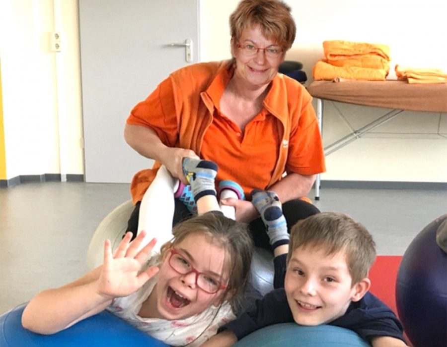 Therapeutin mit zwei Kindern im Kinderraum der Praxis