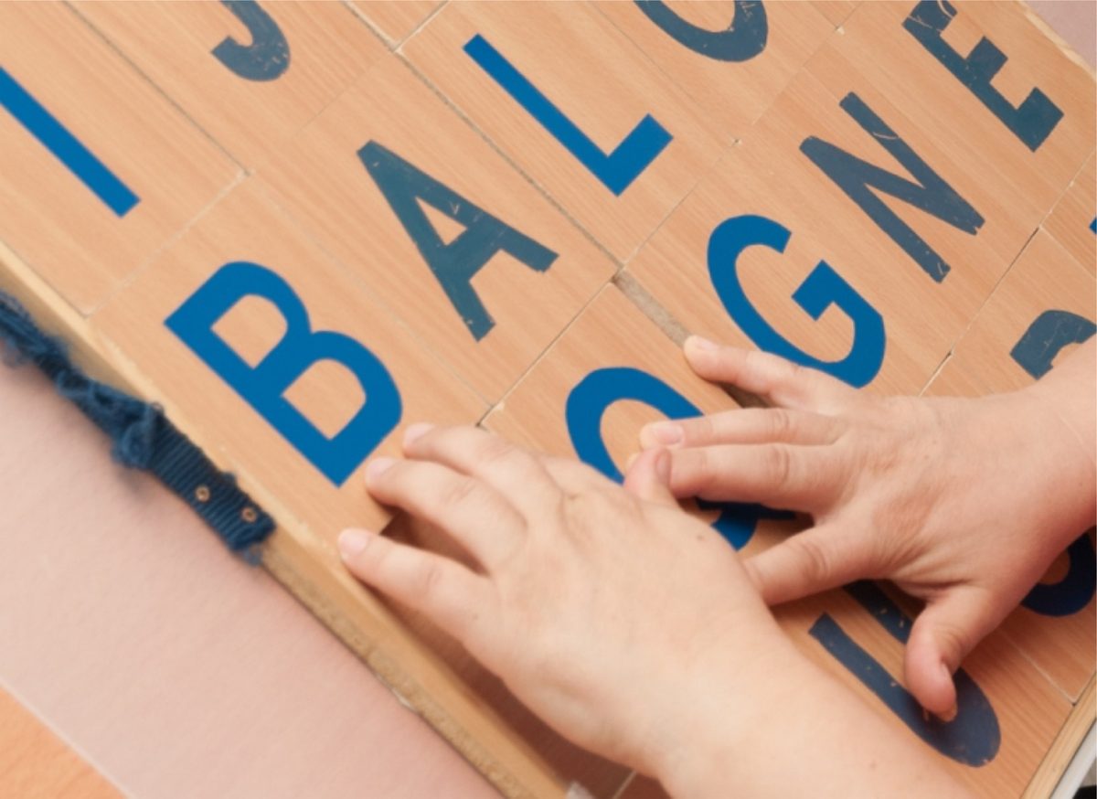 Hände schieben Buchstabentafeln zu einem Wort