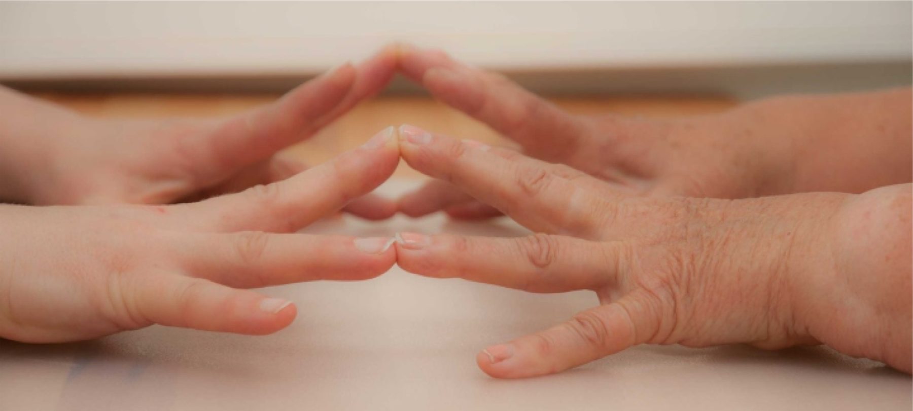 Eine junge und eine ältere Hand berühren sich an den Fingerspitzen