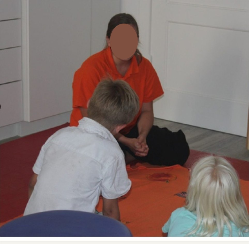 Therapeutin arbeitet mit zwei Kindern auf der Matte