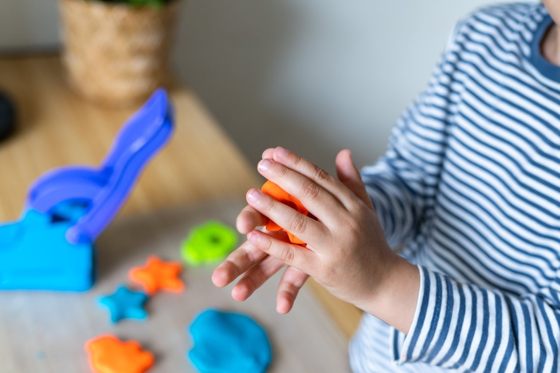 Kind formt bunte Figuren aus Knete