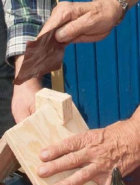 Ältere Hände schleifen ein Werkstück aus Holz