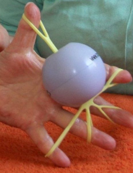 Hand mit Ball und Gummizügen an den Fingern